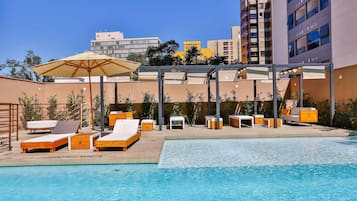 Una piscina al aire libre, sillones reclinables de piscina