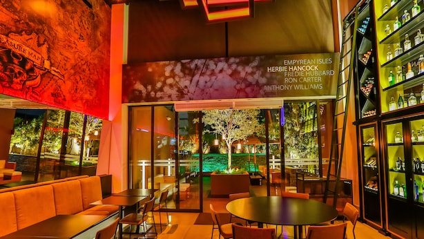 A modern bar area with seating and a bar stocked with bottles. - Radisson RED Campinas (Campinas)