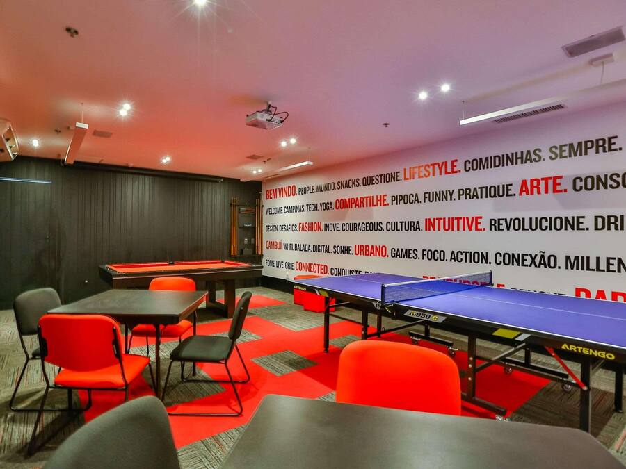 Uma sala de conferências com mesa de pingue-pongue, mesa de bilhar e cadeiras vermelhas.