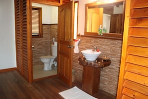 Un baño con paneles de madera, un inodoro, un lavabo y un espejo.