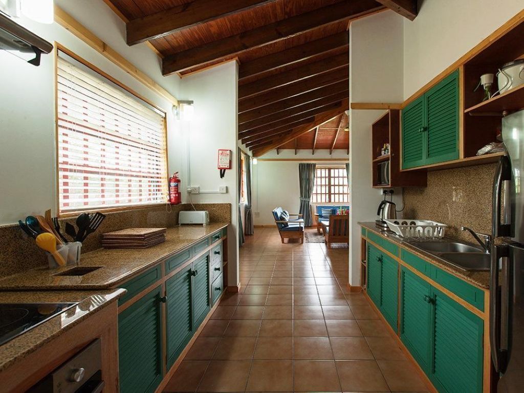 A kitchen with a wooden ceiling, green cabinets, and a tiled floor.