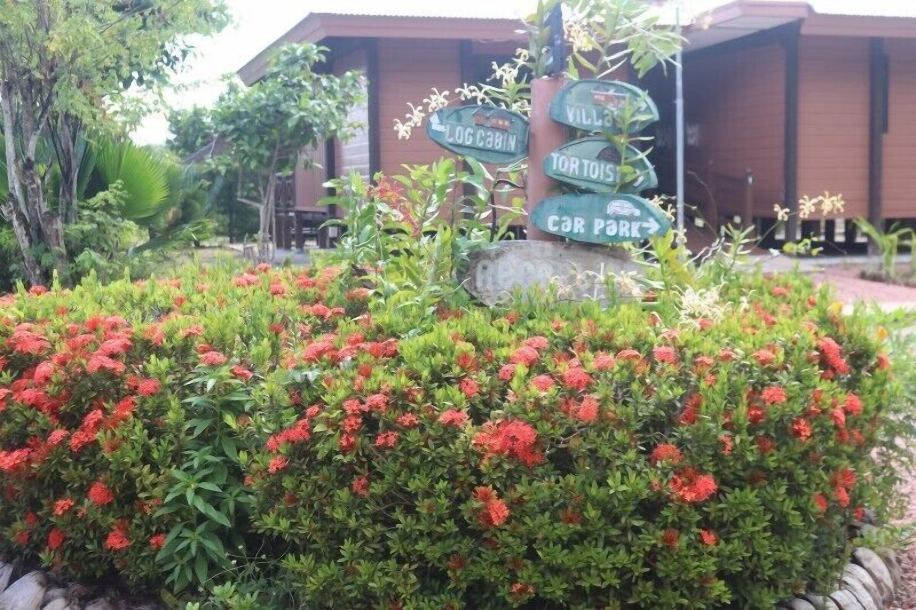 A garden area with a signpost indicating directions to 'Log Cabin,' 'Tortoise,' and 'Car Park.'