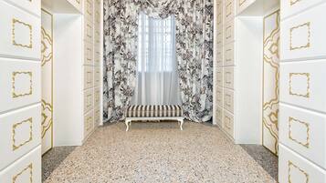 A hallway with a bench, patterned curtains, and decorative wall panels.
