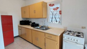 A compact kitchen with a stove, sink, and cabinets. - La Casa de Joy Airport Apartments (St. John's)