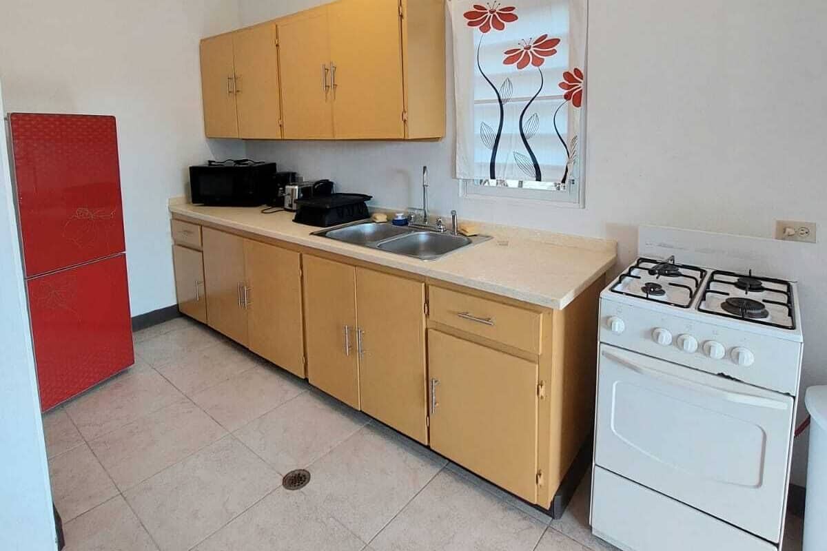 A compact kitchen with a stove, sink, and cabinets.