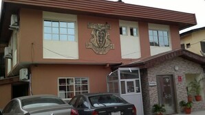 A building with a reception area, two parked cars, and a stone facade. - Esado Suites and Conference Oregun (Lagos)