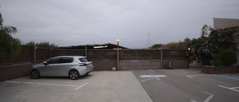 A parking area with a car, a gated entrance, and a building labeled "HOTEL" in the background.
