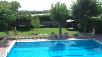 Una piscina rectangular con agua azul cristalina, rodeada por una cubierta de madera y una valla blanca.