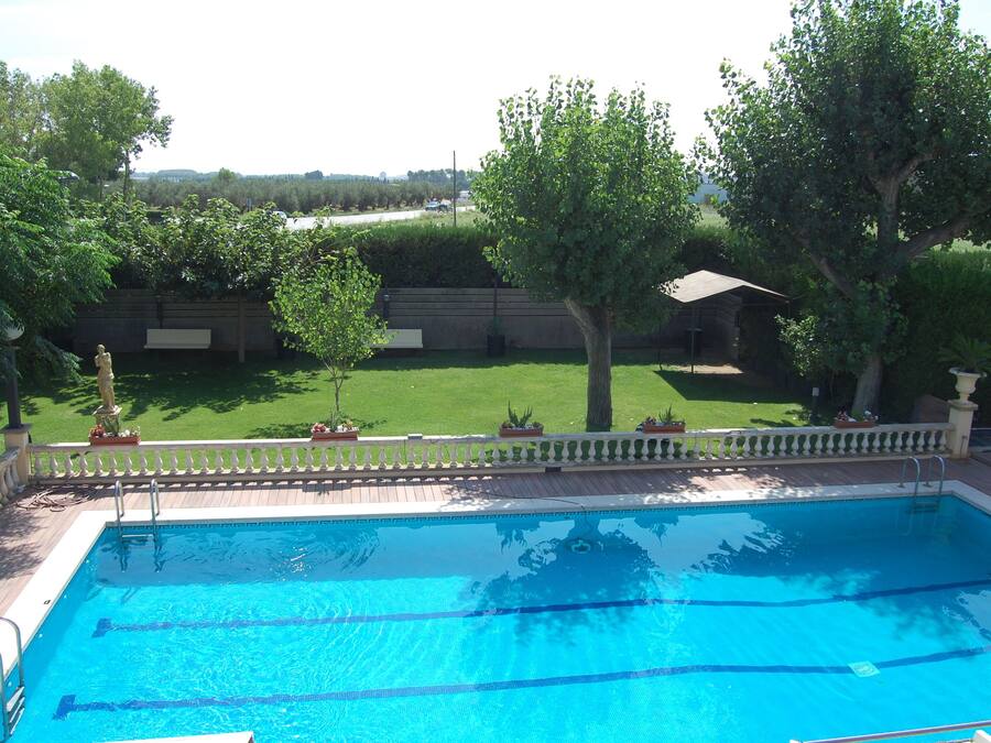 Ein rechteckiger Swimmingpool mit klarem, blauem Wasser, umgeben von einer Holzdielen-Terrasse und einem weißen Zaun.