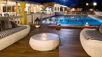 Een buitenzwembad, ligstoelen bij het zwembad