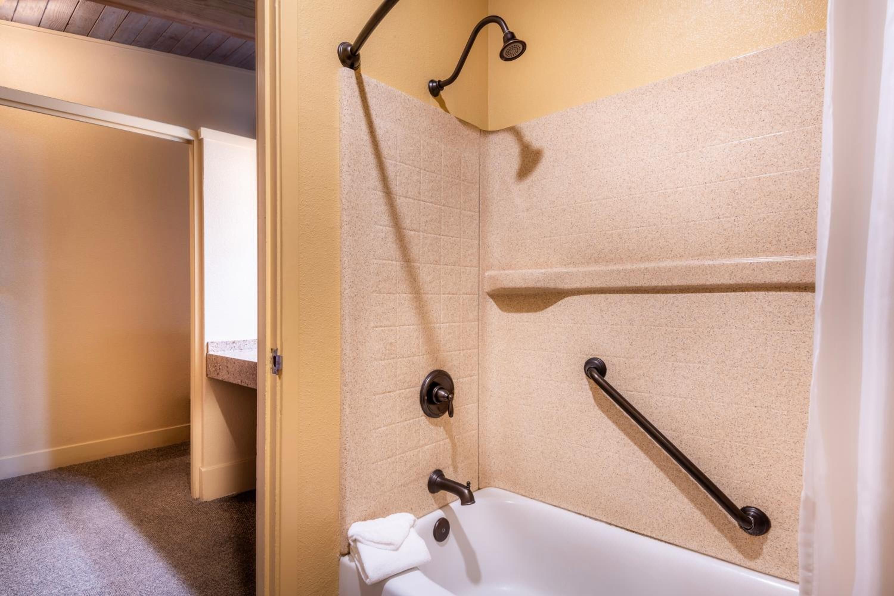 Ein Badezimmer mit einer Badewanne, Haltegriffen und einem Handtuchhalter.