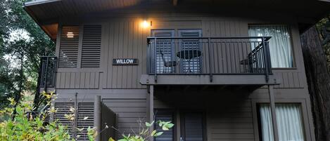 A two-story building with a balcony, a sign reading "WILLOW," and a door with a doormat.