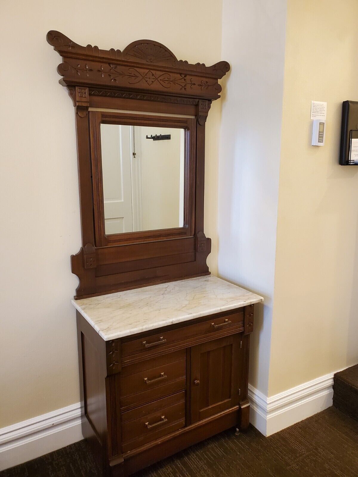A wooden vanity with a marble countertop and a mirror above it.