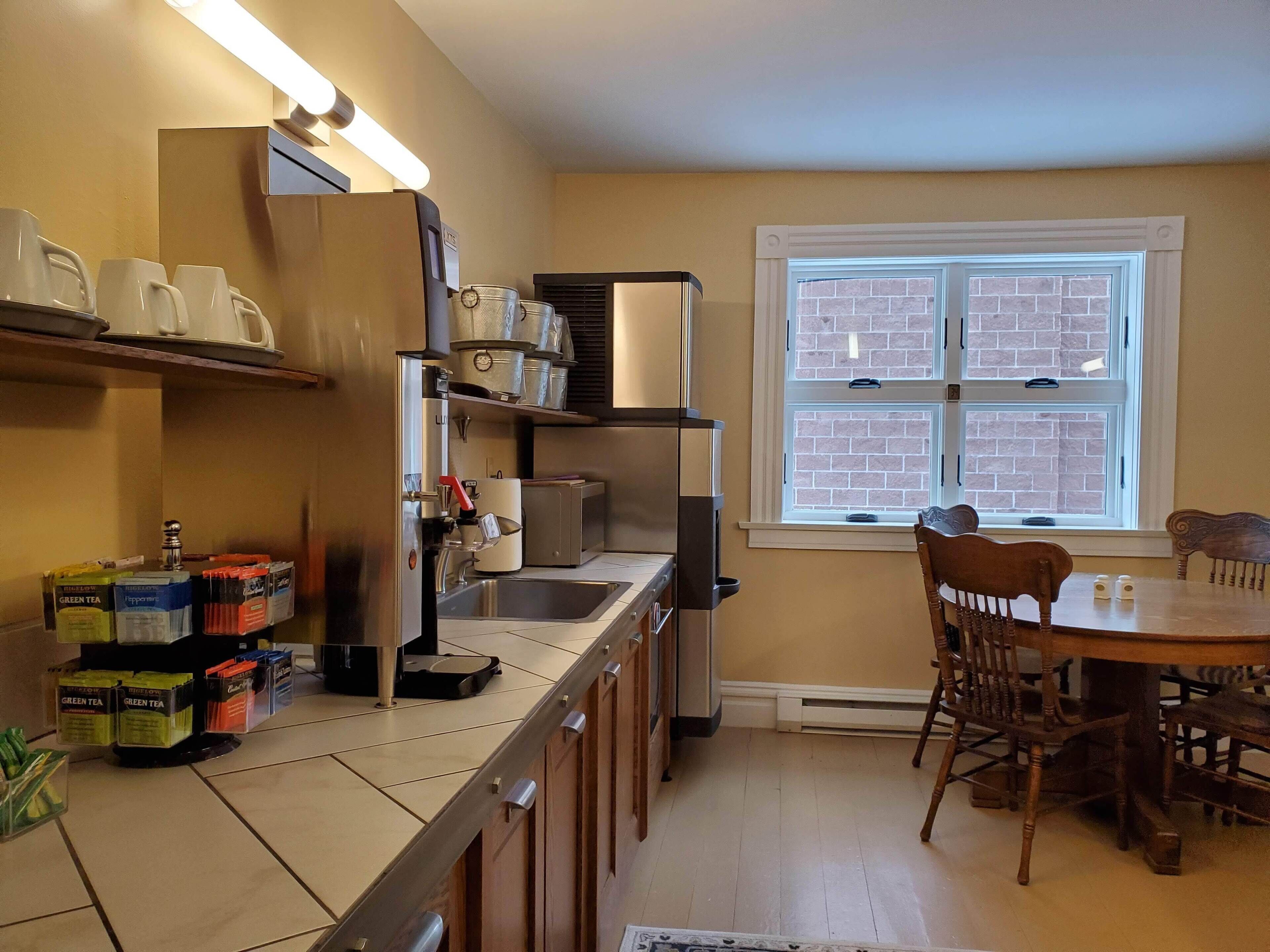 A kitchen with a built-in stove, a sink, and a window with a view of a brick wall. There is a dining table with chairs and a small rug.