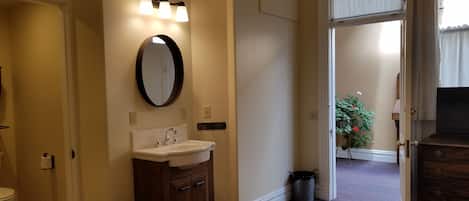 A hotel bathroom with a sink, mirror, and toilet.