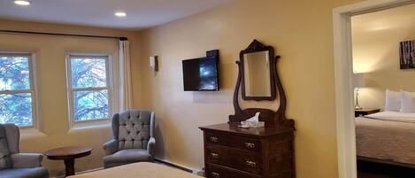 Una habitación de hotel con una cama grande, una silla, un aparador, un televisor y un espejo.