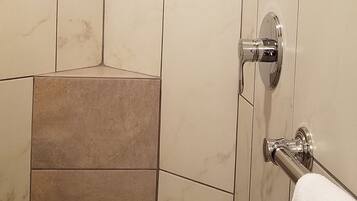 A shower area with beige tiles and a showerhead.