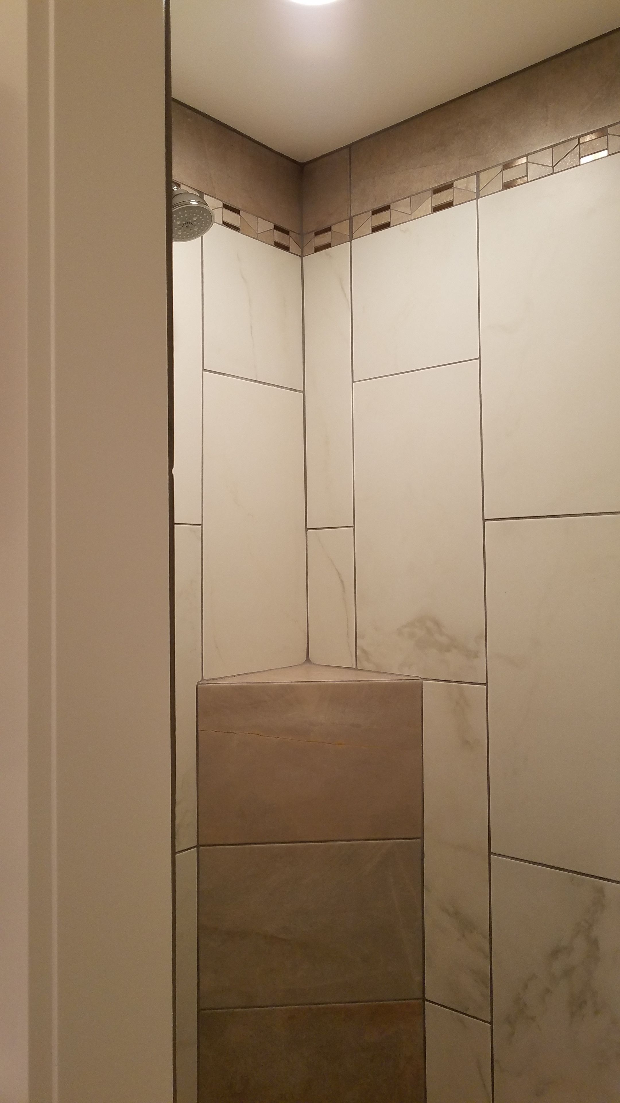 Eine geflieste Dusche mit Marmoroptik und einer kleinen Duschbrause.
