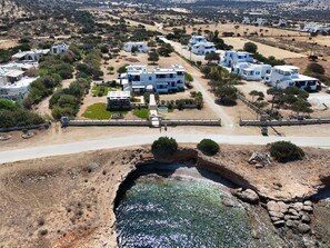 An aerial view of a coastal village with white buildings, a central courtyard, and a rocky shoreline. - Ammoudia Studios (Naxos)