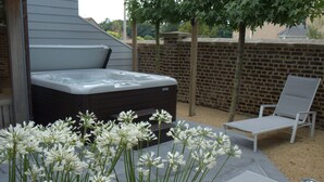 A hot tub, a lounge chair, and a flower arrangement in an outdoor setting. - Hotel Vorsen (Gingelom)