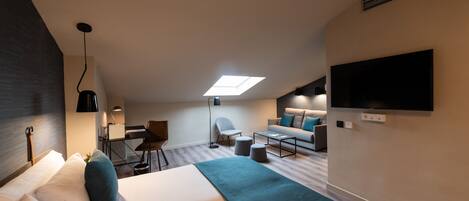 Una habitación de hotel moderna con una cama grande, un escritorio, una silla, un sofá, un televisor y un tragaluz.