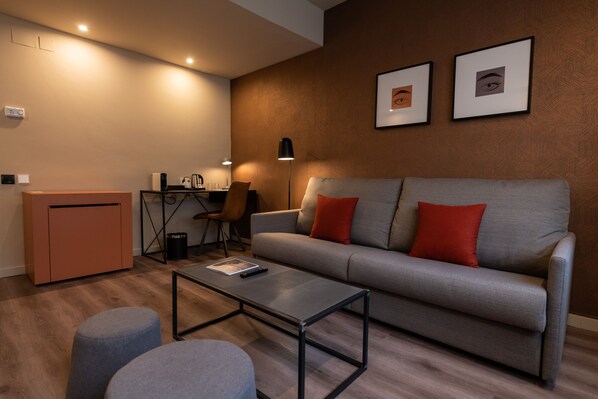 A modern living room with a grey sofa, red cushions, a coffee table, and a small cabinet. -  Atenea Rekord Suites Barcelona (Barcelona)