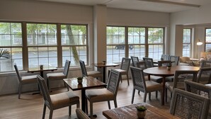 Un restaurant doté de grandes fenêtres, de tables en bois et de chaises en osier.