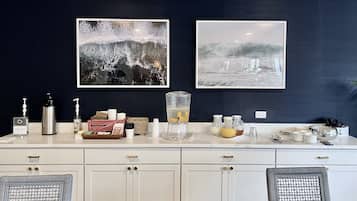 Une cuisine moderne avec des meubles blancs, un plan de travail en marbre et deux tableaux abstraits encadrés.