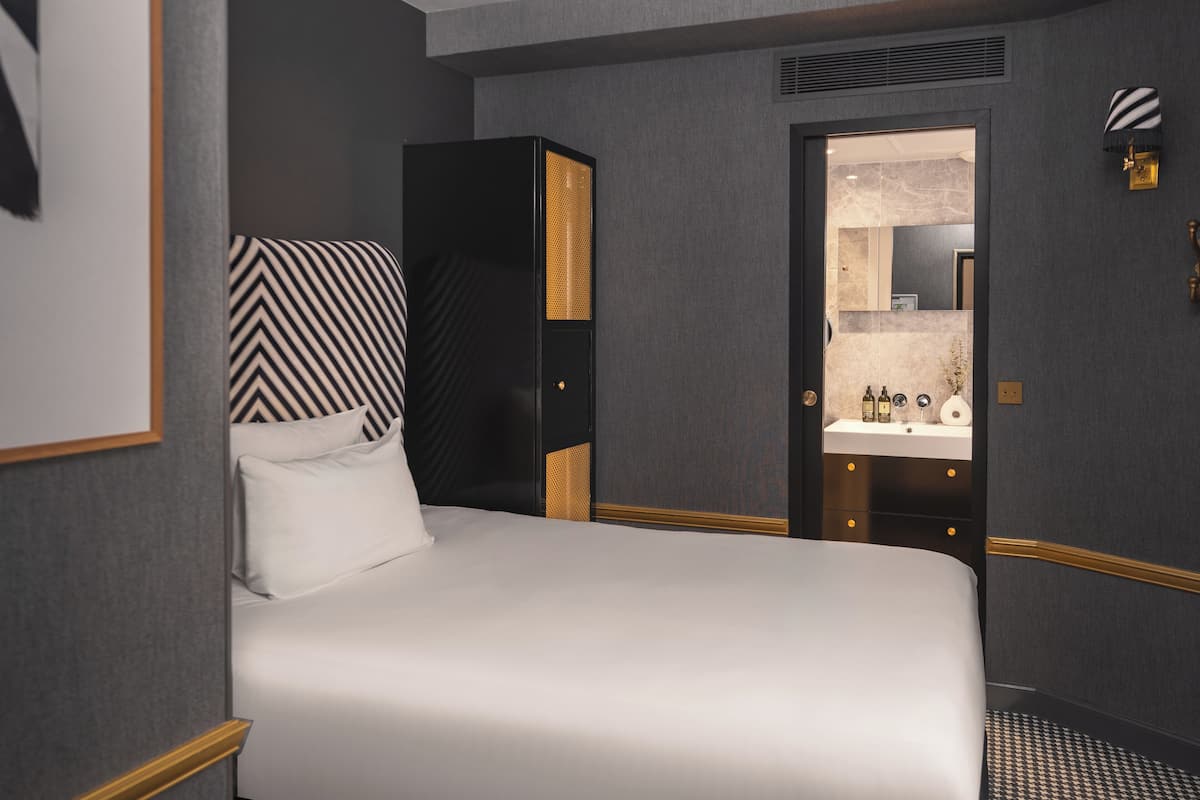 Une chambre d’hôtel avec un grand lit, une armoire, une coiffeuse avec un miroir et un tableau encadré au mur.