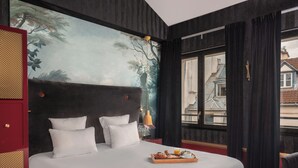 Habitación de hotel con una cama grande, un cuadro en la pared, una ventana con cortinas y una bandeja con alimentos para el desayuno.