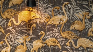 Una escalera con un muro decorado con estampados de flamencos y follaje.