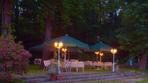 Espace extérieur aménagé avec des parasols et des chaises, entouré d’arbres et de marches.