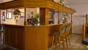 Un espace d’accueil avec un comptoir en bois, des tabourets de bar et un globe posé sur le dessus.