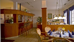 Un espace repas avec des meubles en bois, un bar et une grande fenêtre agrémentée de rideaux.
