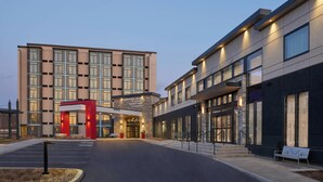 A modern hotel entrance with a red canopy, a parking lot, and a well-lit facade. - Courtyard by Marriott Oshawa (Oshawa)
