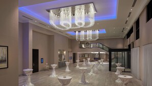 A spacious hotel lobby with multiple round tables, a grand chandelier, and a staircase leading to an upper level. - Courtyard by Marriott Oshawa (Oshawa)