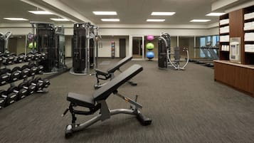 A gym with weight machines, dumbbells, exercise balls, and a treadmill.