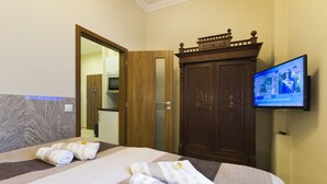 Une chambre d’hôtel équipée d’un lit, de serviettes, d’une armoire en bois et d’un téléviseur diffusant un programme d’information.