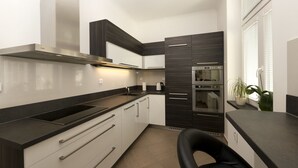 Une cuisine moderne avec un plan de travail noir, des appareils en acier inoxydable et des meubles de cuisine en bois foncé.