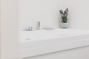 A white bathroom with a modern sink, a tall faucet, and a potted lavender plant. - The Artists' Palace Florence (Florence)