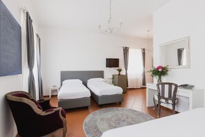 A hotel room with two beds, a desk, a chair, a TV, and a chandelier. - The Artists' Palace Florence (Florence)