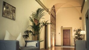 A living room with a sofa, a large plant, and a door leading to another room. - The Artists' Palace Florence (Florence)