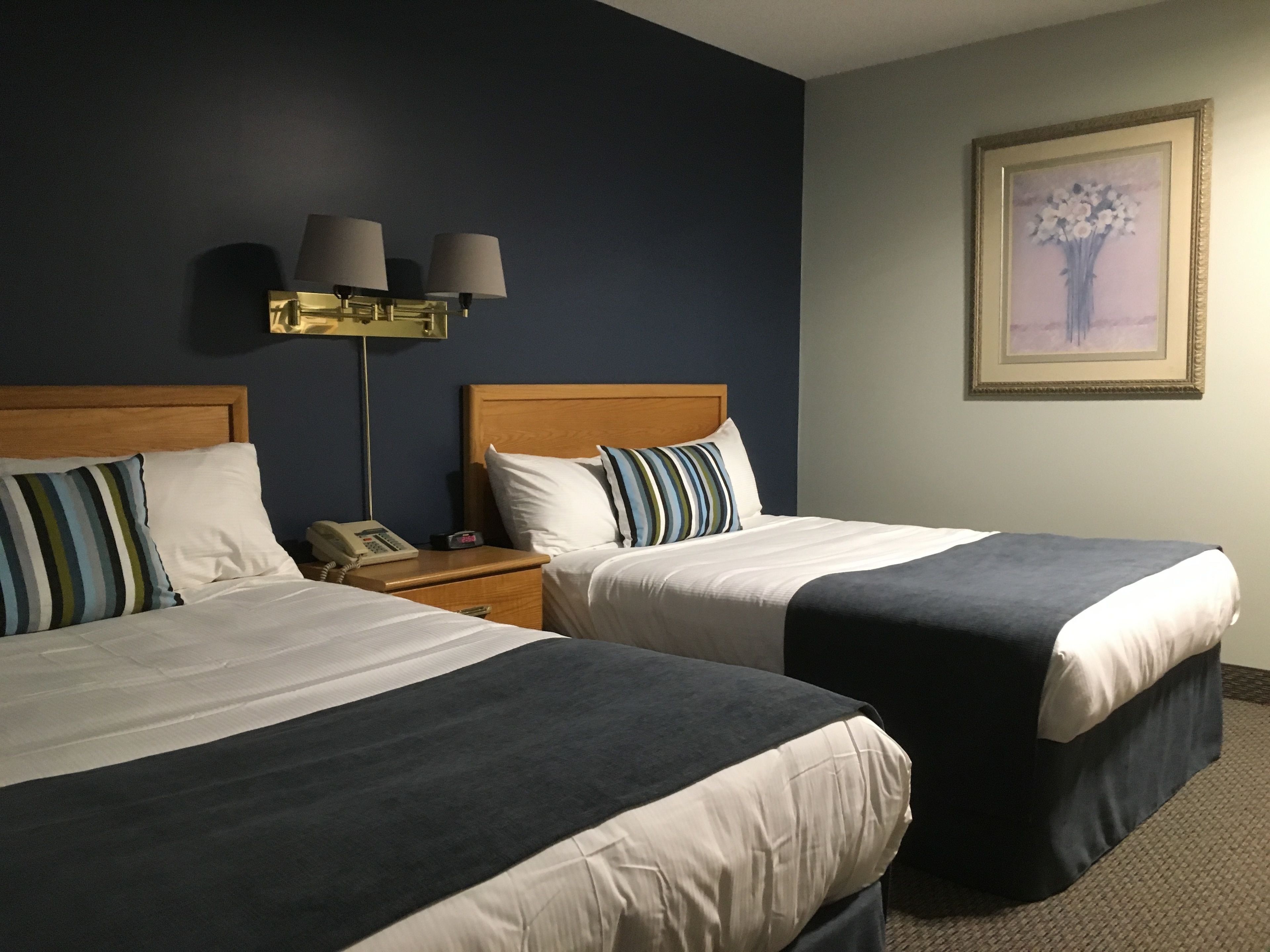 Une chambre d’hôtel avec deux lits, une table de chevet avec un téléphone et une lampe fixée au mur.