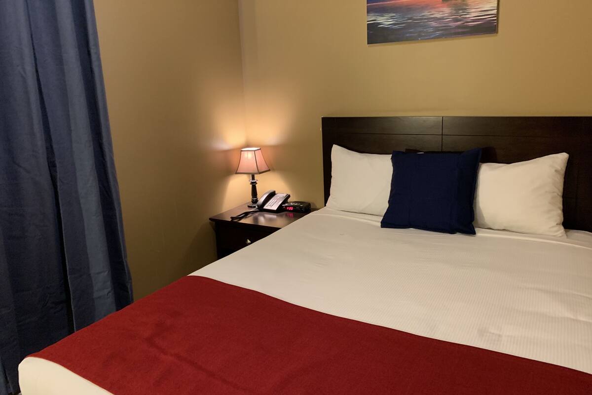 Une chambre d’hôtel avec un lit, une table de chevet avec une lampe et un tableau au mur.