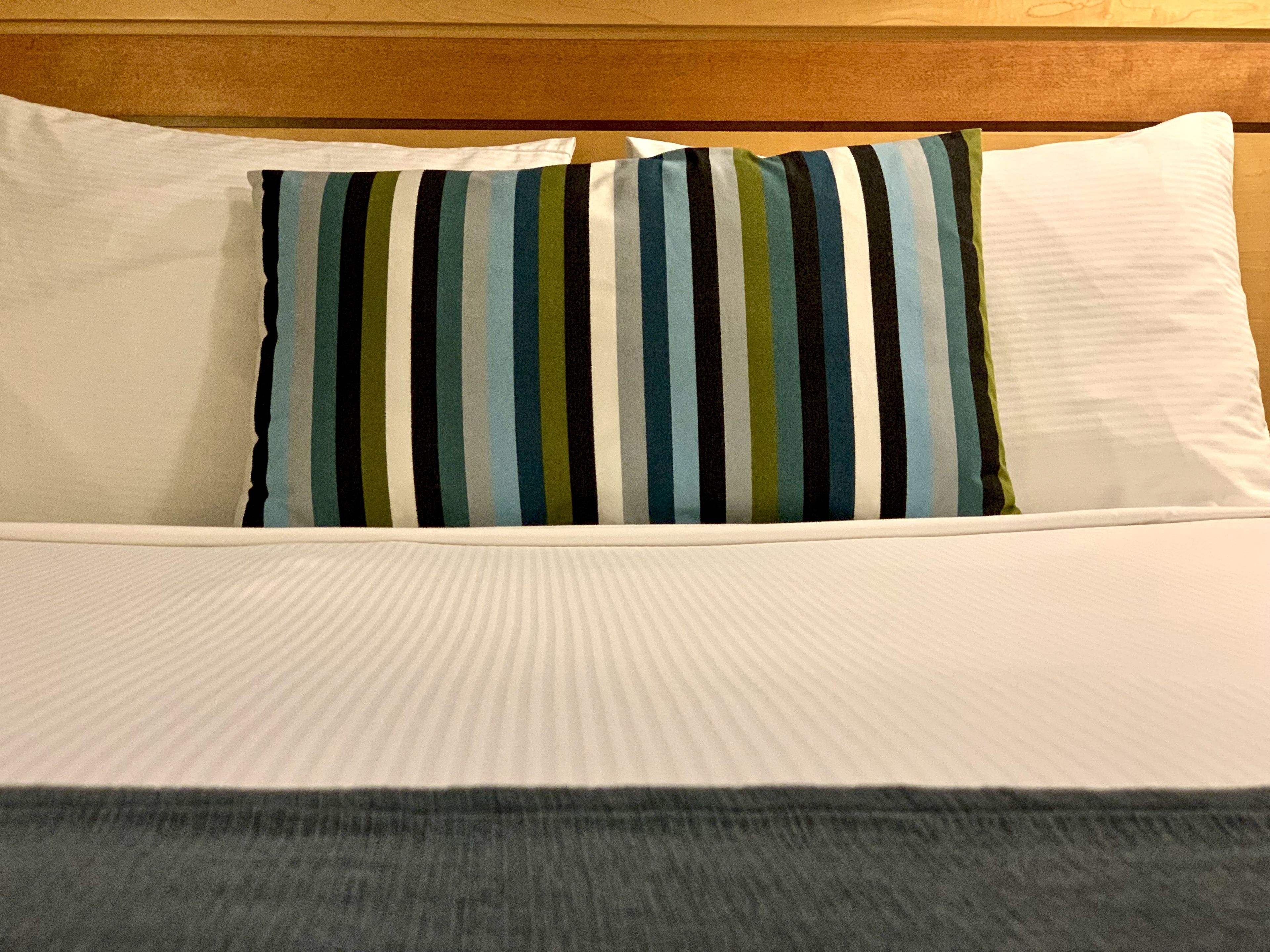Una cama con ropa de cama blanca y almohadas a rayas.