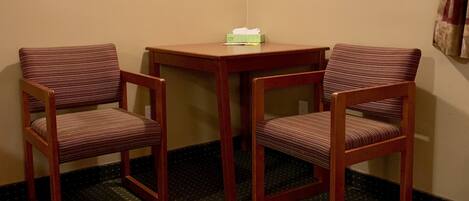 A corner room with two wooden chairs, a small table, and a hanging light fixture.