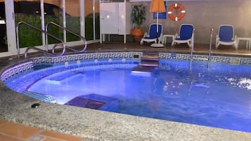 Una piscina con borde decorativo, un flotador salvavidas y una silla cerca de la pileta.