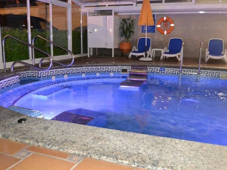 Una piscina con borde decorativo, un flotador salvavidas y una silla cerca de la pileta.