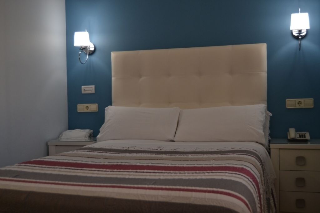 A hotel room with a bed, two bedside lamps, a nightstand, and a telephone.