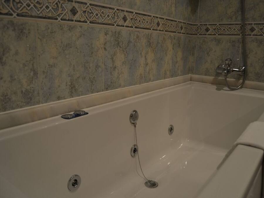 A bathtub with a showerhead and a control panel.
